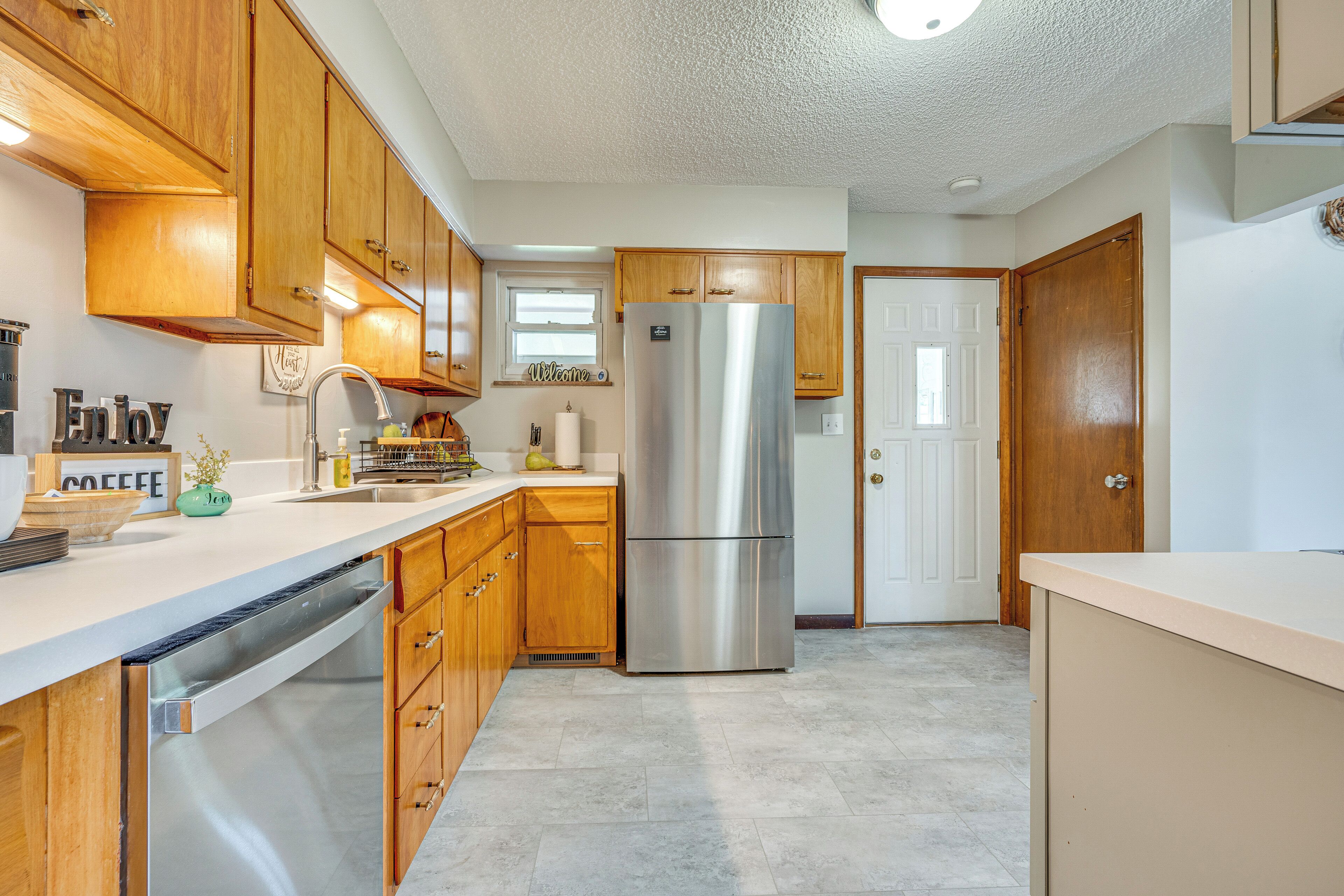 A kitchen with wooden cabinets, a stainless steel refrigerator, and a dishwasher.