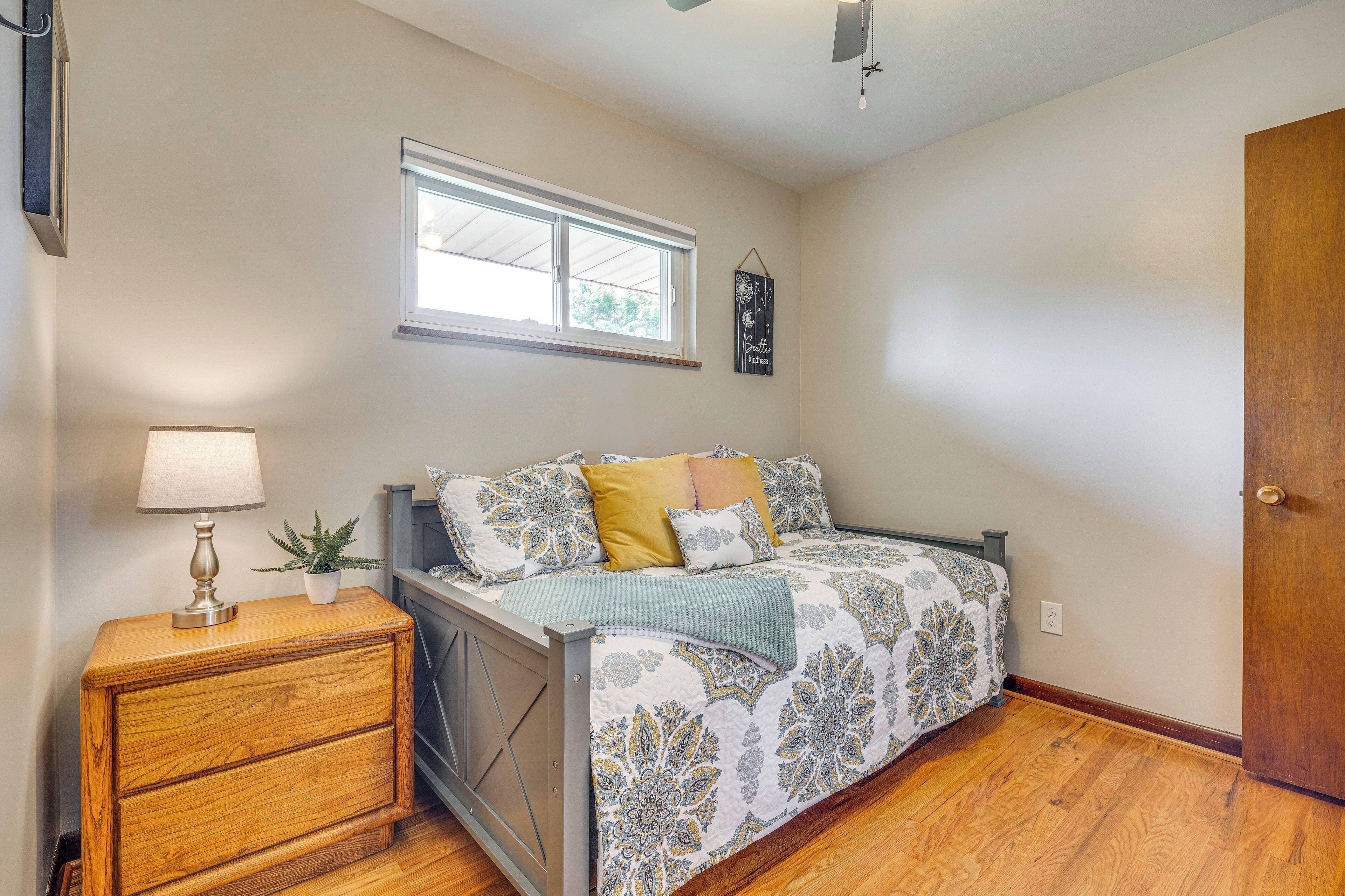 A bedroom with a bed, bedside table, lamp, and a window.