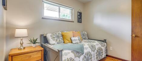 A bedroom with a bed, bedside table, lamp, and a window.