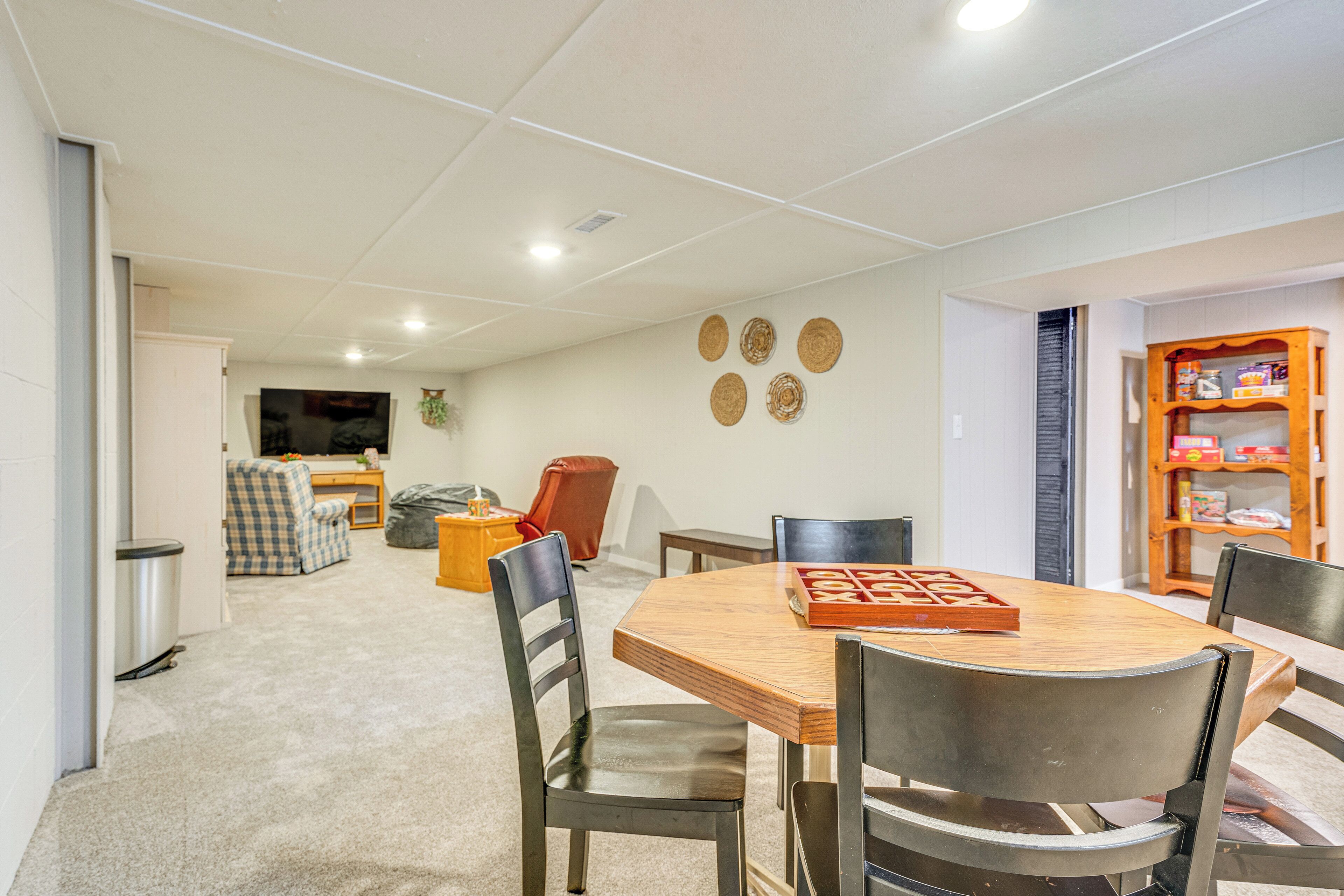 A dining area with a wooden table and four chairs, a bookshelf, and a television in the background.
