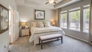 A bedroom with a bed, bedside lamps, a ceiling fan, and large windows. - Walk to Brazos County Expo: Elegant Home w/ Grill! (Bryan)