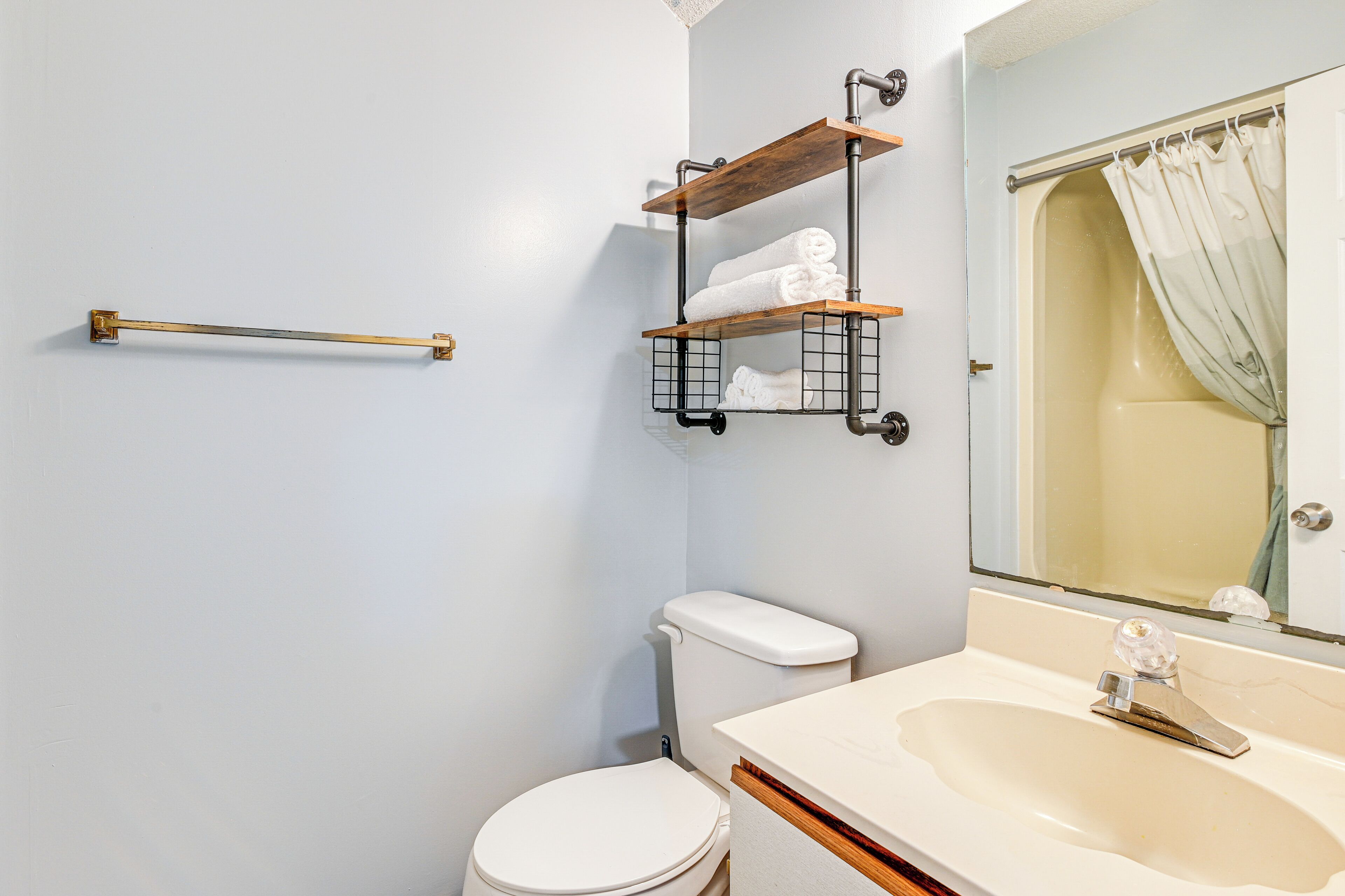 A bathroom with a white toilet, a sink with a mirror, and a towel rack with towels.