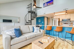 A modern living room with a sofa, coffee table, and a spiral staircase leading to an upper level. - 2 Mi to Surfside Beach: Coastal Escape w/ Balcony! (Surfside Beach)