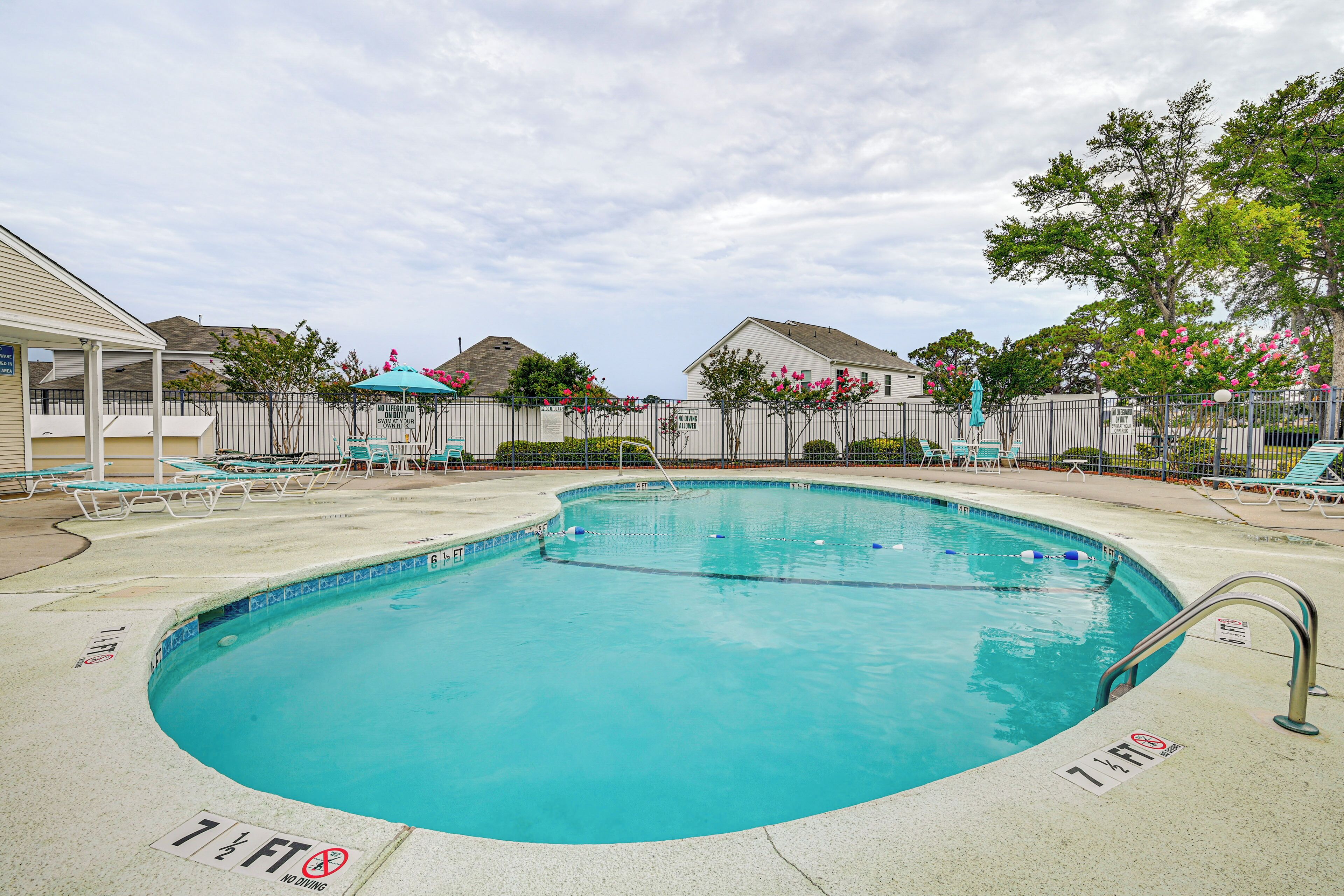 A swimming pool with a diving board, lounge chairs, and a covered seating area.