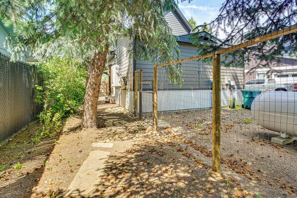 A fenced backyard with a tree, a concrete path, and a parked car.