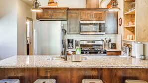 A kitchen with wooden cabinets, granite countertops, stainless steel appliances, and pendant lighting. - Charming Donnelly Home - 1 Mi to Lake Cascade! (Donnelly)