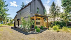 A two-story house with a covered porch, a gravel driveway, and a landscaped garden. - Charming Donnelly Home - 1 Mi to Lake Cascade! (Donnelly)
