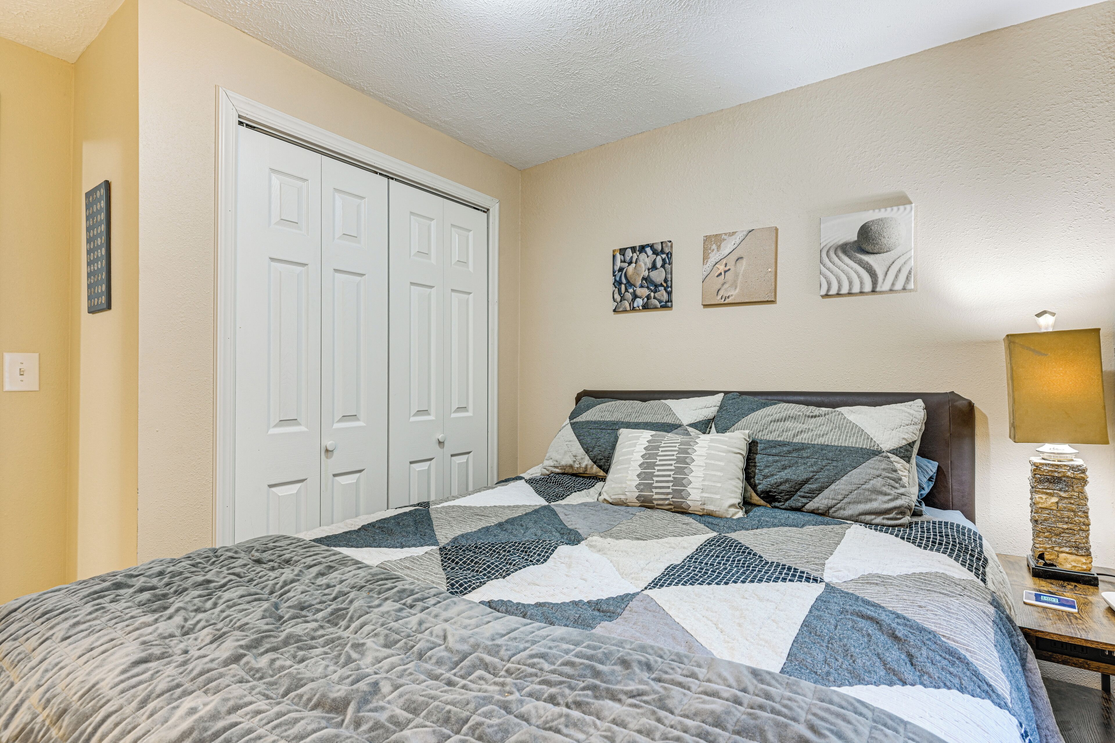 A bedroom with a bed, a nightstand, a lamp, and a door.