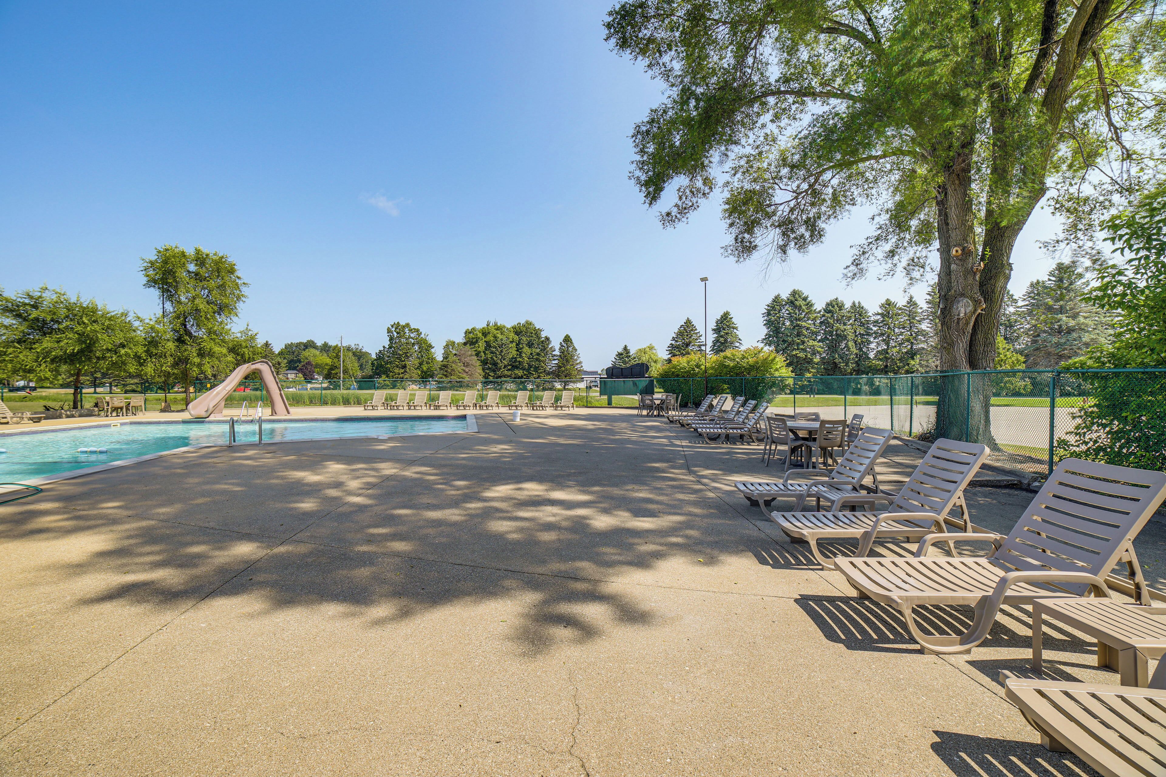 A pool area with a slide, lounge chairs, and a fenced deck.