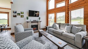 A spacious living room with a fireplace, large windows, and a modern sofa set. - Scenic Getaway w/ Deck: 7 Mi to Mammoth Cave Park! (Brownsville)