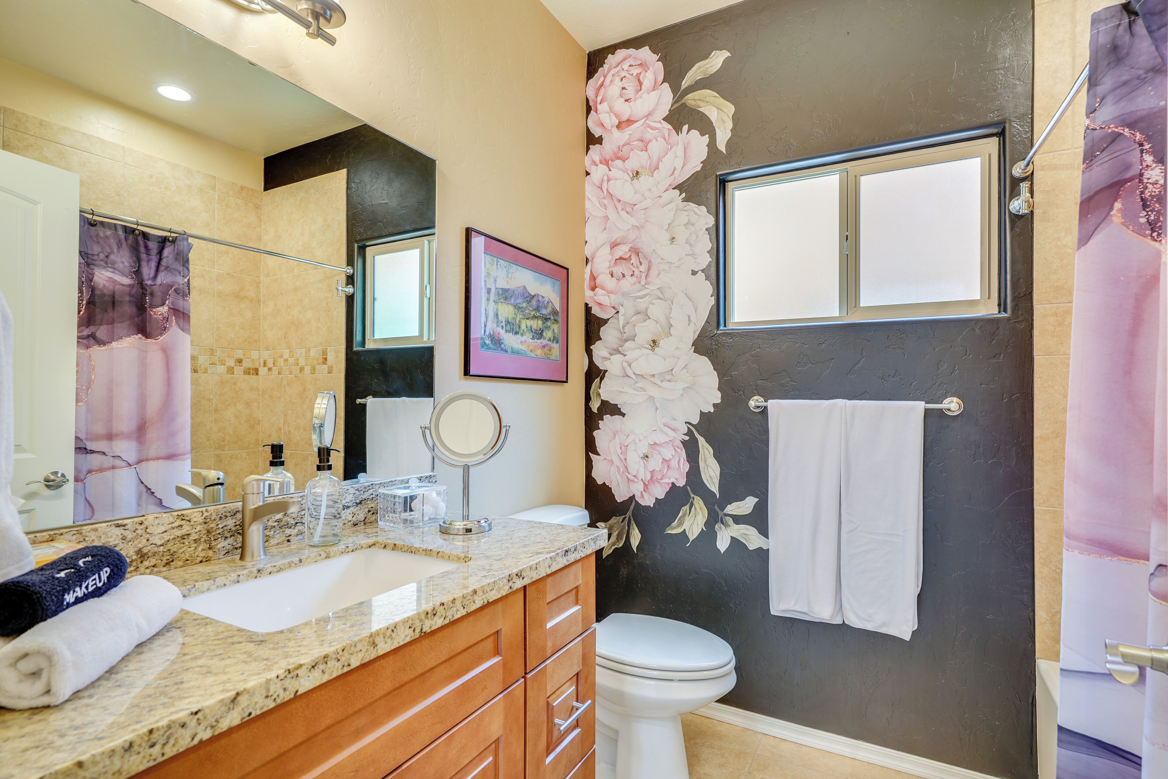 A bathroom with a marble countertop, a sink, a mirror, a toilet, and a shower curtain.