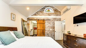 Ein Schlafzimmer mit einem großen Bett, einem Holzschrank und einem Fernseher an der Wand.