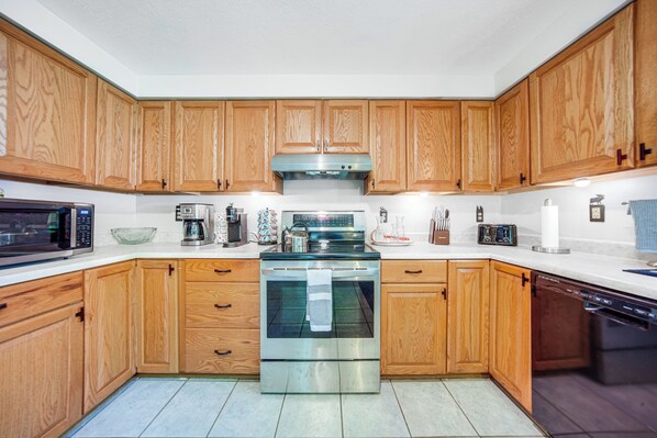 Una cocina moderna con armarios de madera, electrodomésticos de acero inoxidable y piso de baldosas.