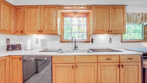 A kitchen with wooden cabinets, a double sink, and a dishwasher. - Pet-friendly Espyville Home w/ Yard & Fire Pit! (Linesville)