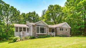 A two-story stone house with a wrap-around porch, a large bay window, and a well-maintained lawn. - Pet-friendly Espyville Home w/ Yard & Fire Pit! (Linesville)