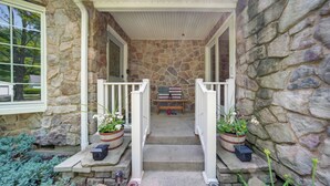 A stone house with a porch, two potted plants, and a bench. - Pet-friendly Espyville Home w/ Yard & Fire Pit! (Linesville)