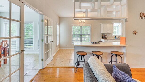 A modern kitchen with a central island, bar stools, and a dining area with a table and chairs. - Family-friendly Harrells Home w/ Fire Pit + Kayaks (Harrells)