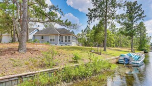 A house with a dock extending into a calm body of water, surrounded by trees. - Family-friendly Harrells Home w/ Fire Pit + Kayaks (Harrells)