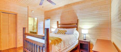 Ein Schlafzimmer einer Holzhütte mit Bett, Nachttisch und Deckenventilator.