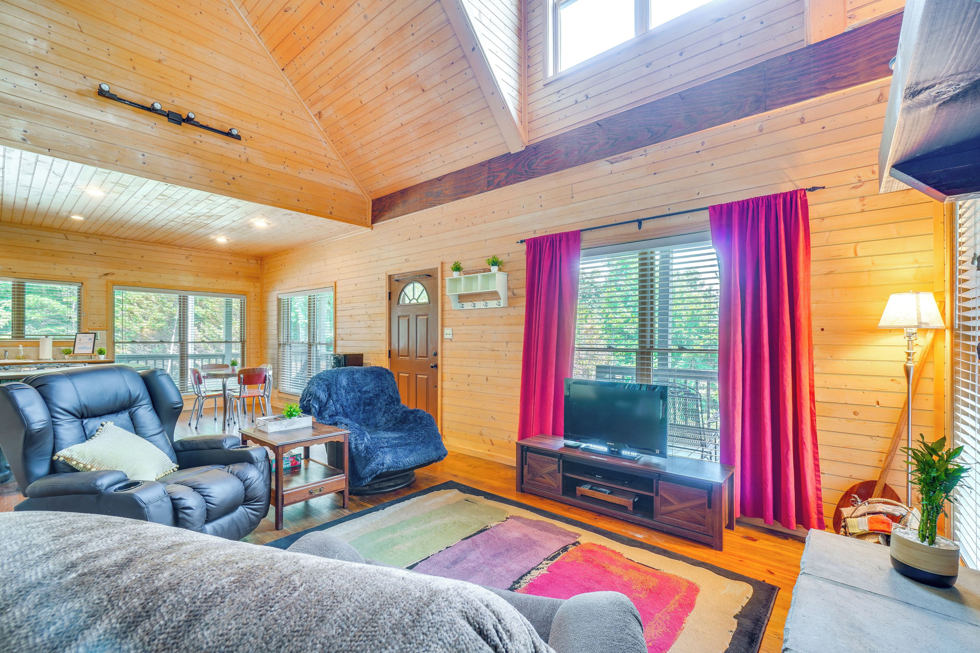 A cozy cabin interior with a leather sofa, a television, and a dining area.