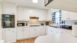 A modern kitchen with white cabinets, a built-in oven, a microwave, and a coffee maker. - Cozy Mullins Retreat w/ Backyard & Covered Porch! (Mullins)