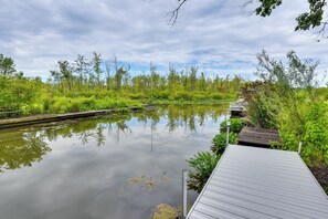 A calm water body with a wooden dock extending into it, surrounded by lush greenery and trees. - Charming Reading Home w/ Lake Views & Private Dock (Reading)
