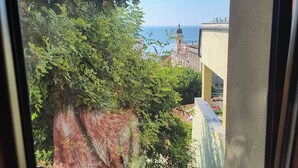 A view from a window overlooking a courtyard with a building and a clear sky.