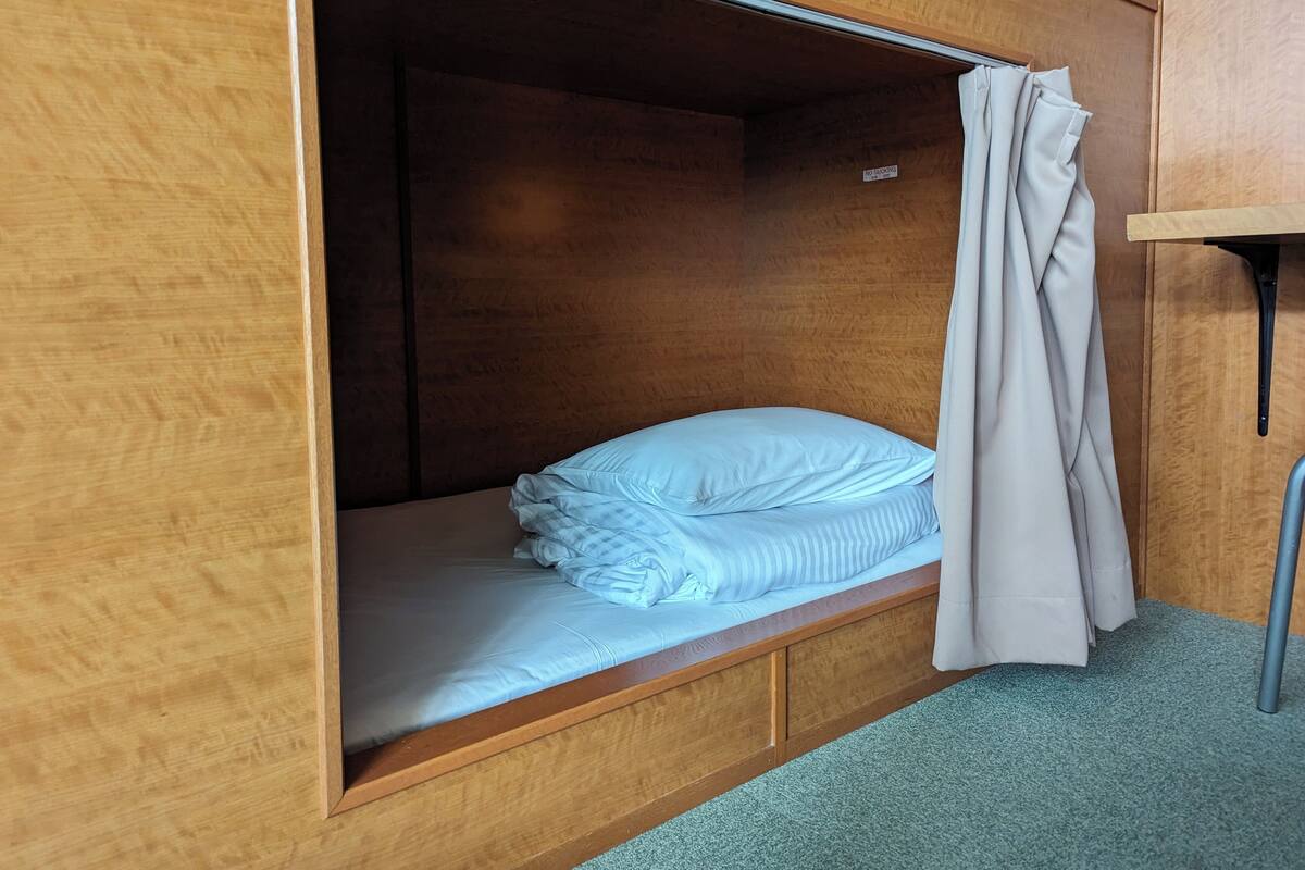 A single bed with a wooden headboard and a curtain.