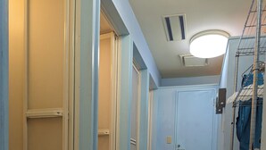 A narrow hallway with blue walls, a light-colored floor, and a door at the end. - Ace Inn Shinjuku - Hostel (Tokyo)