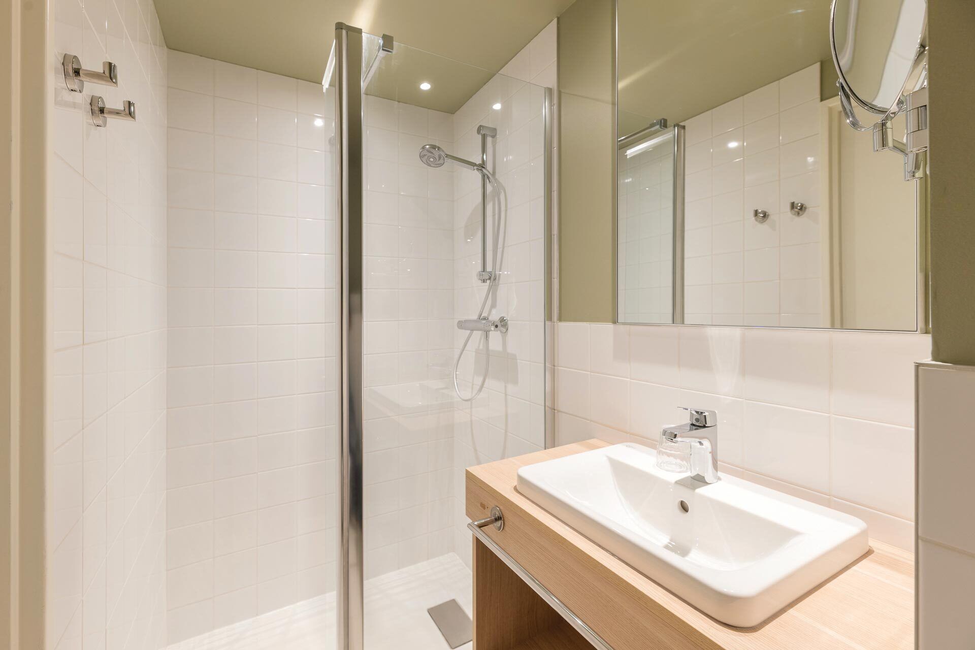 A modern bathroom with a glass-enclosed shower, a wooden vanity with a white sink, and a large mirror.