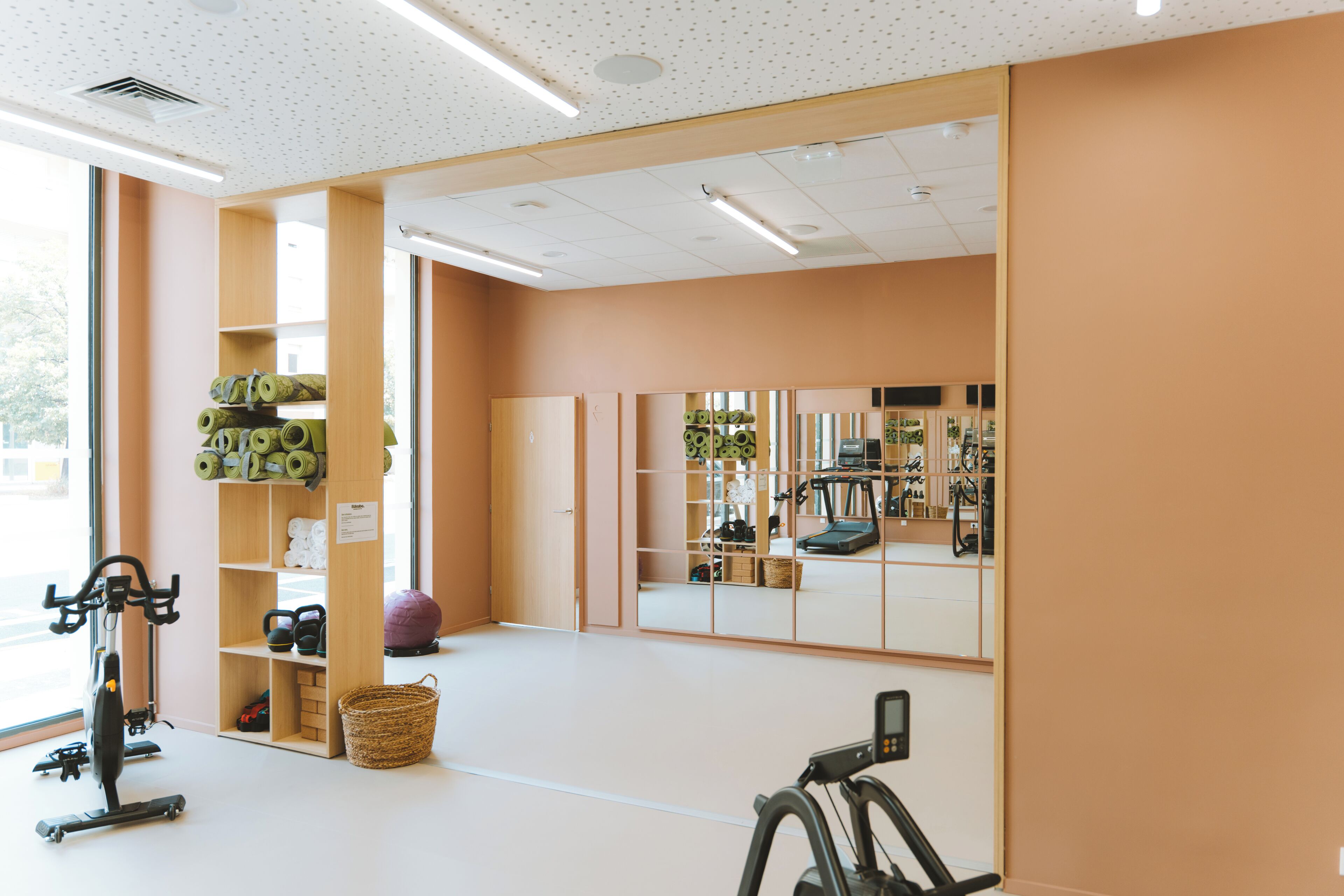A gym with exercise equipment, a treadmill, and a mirrored wall.
