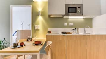 Une cuisine moderne avec des meubles en bois, un four à micro-ondes encastré et un coin repas avec une table dressée pour deux personnes.