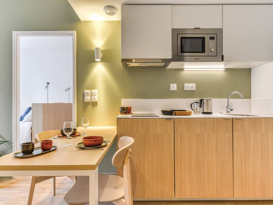 Eine moderne Küche mit Holzausstattung, einer eingebauten Mikrowelle und einem Essbereich mit Tisch für zwei Personen.