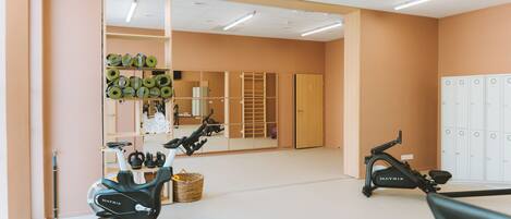 A gym with exercise bikes, a mirrored wall, and lockers.