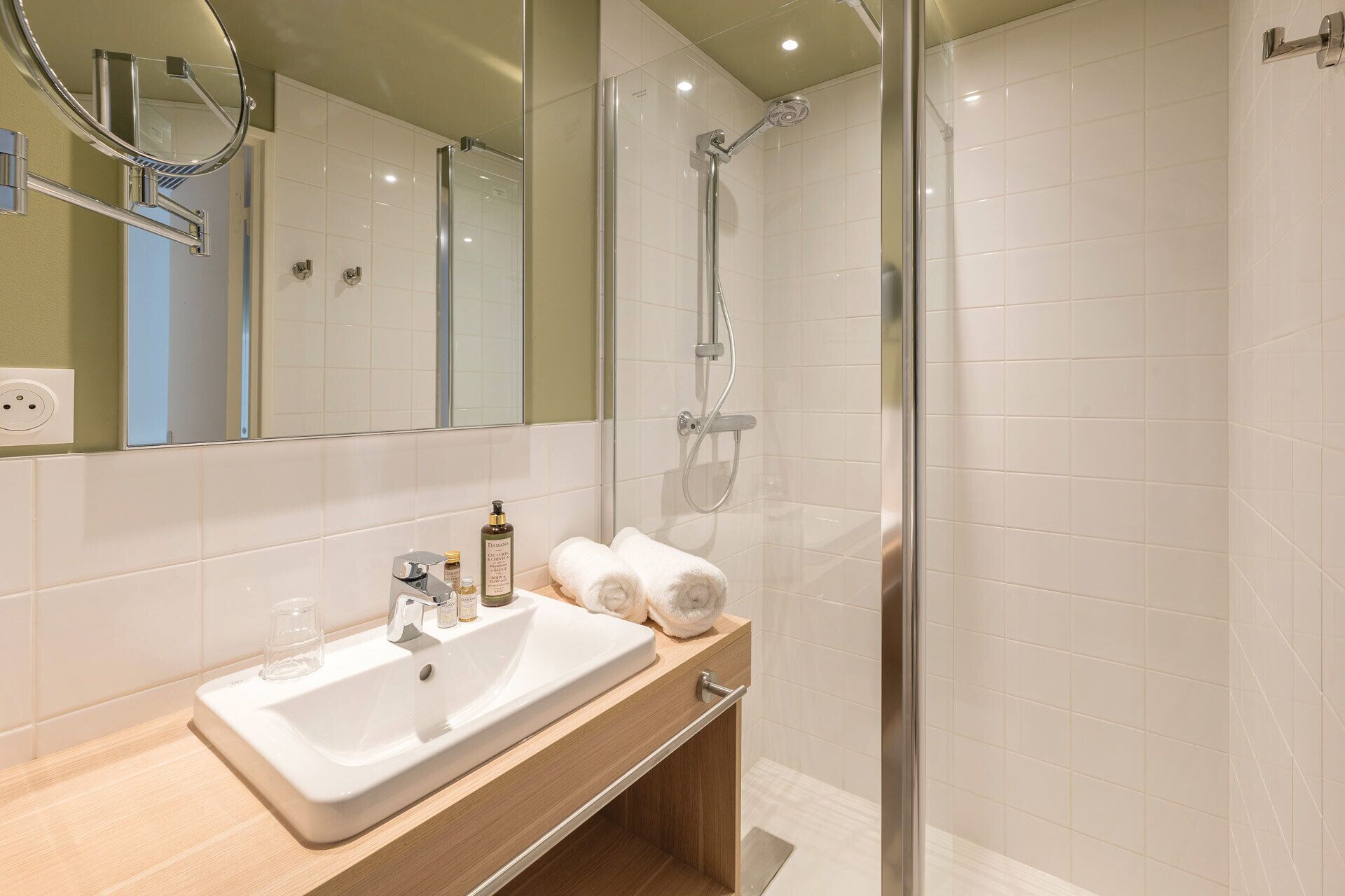 Une salle de bain moderne avec un lavabo blanc, un miroir et une douche.