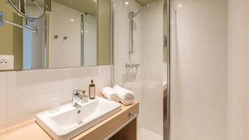 Une salle de bain moderne avec un lavabo blanc, un miroir et une douche.