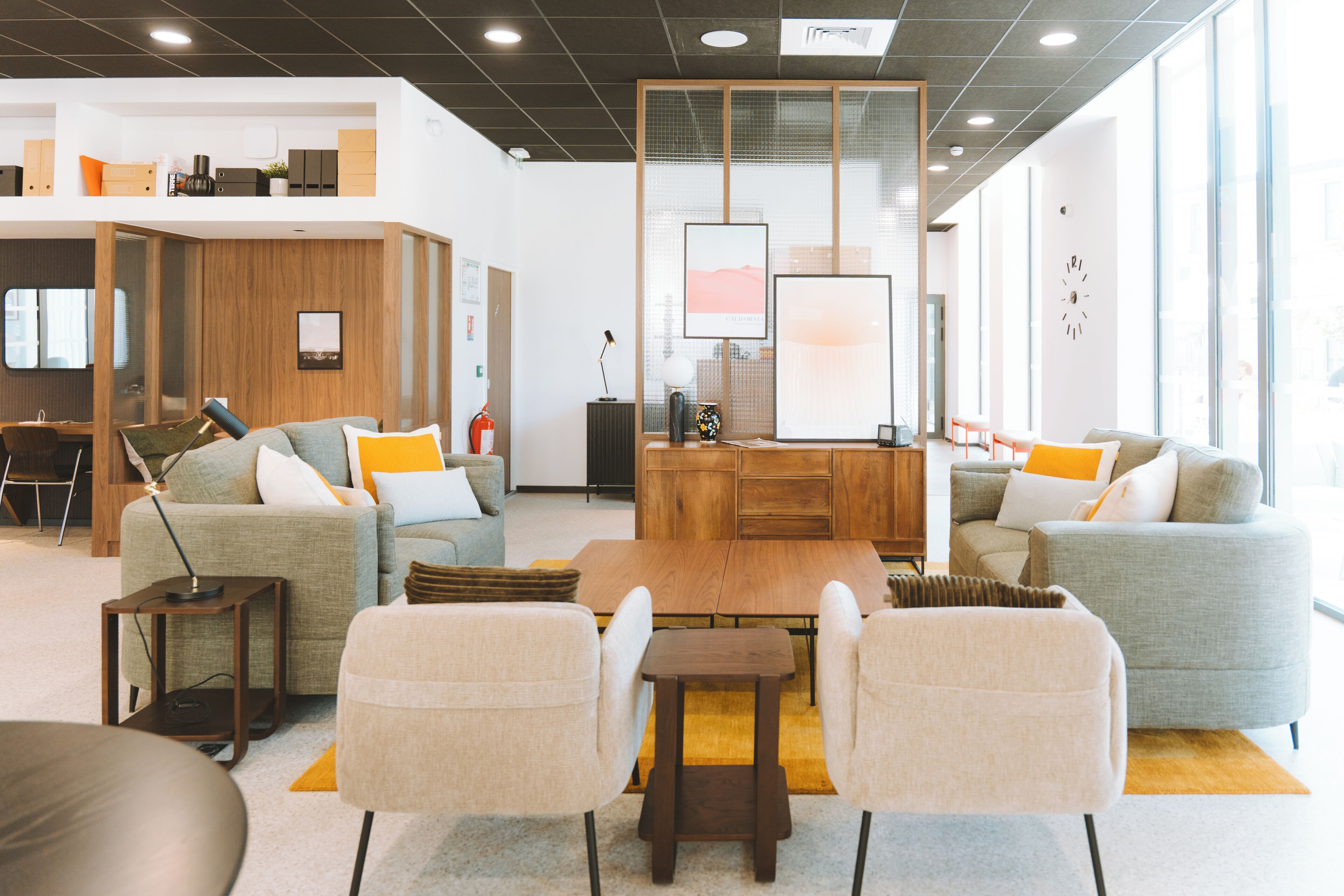 A modern living room with sofas, a coffee table, and a TV. There is a wooden cabinet and a small table with a lamp.