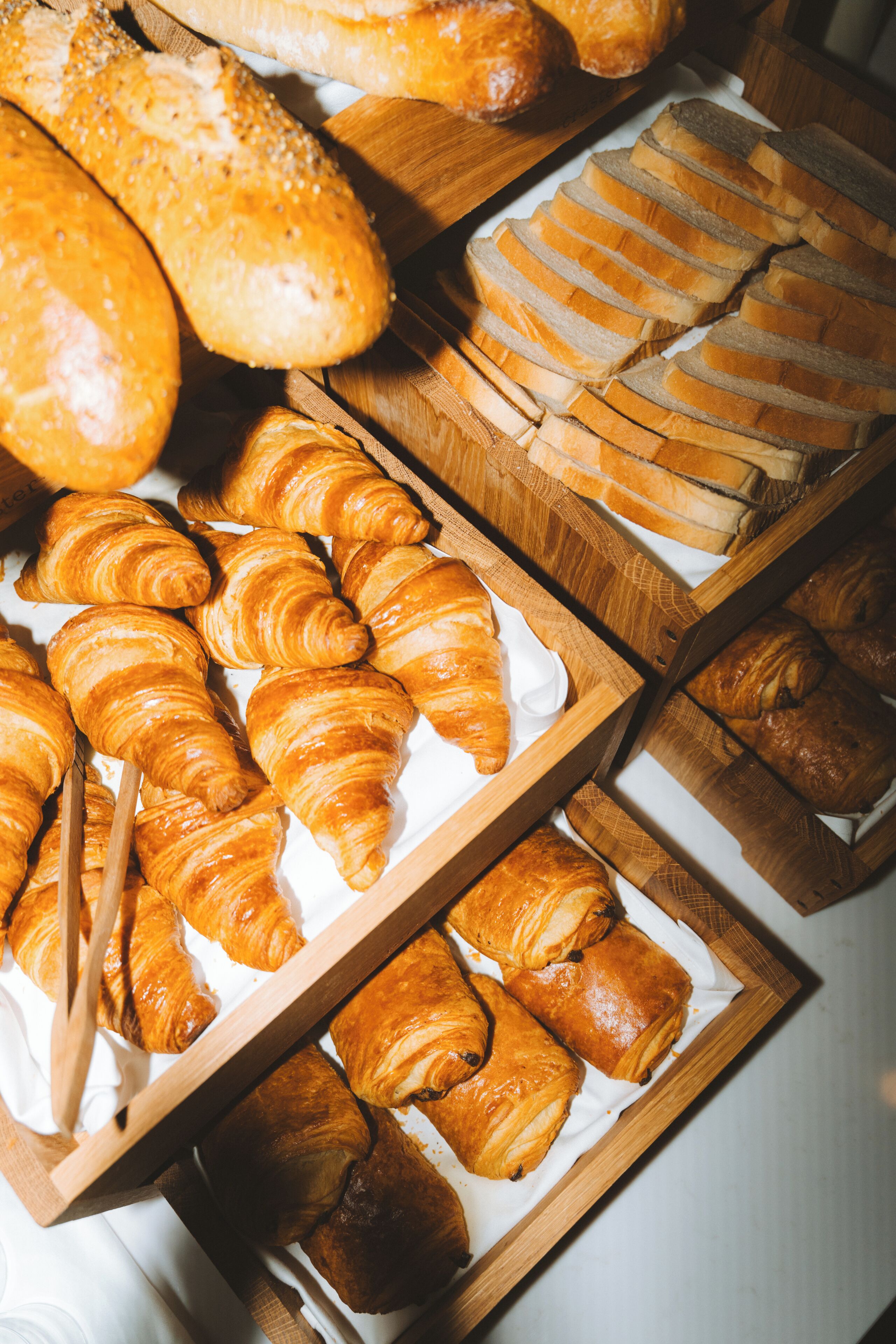 Une variété de pains et de viennoiseries présentés sur des plateaux en bois.
