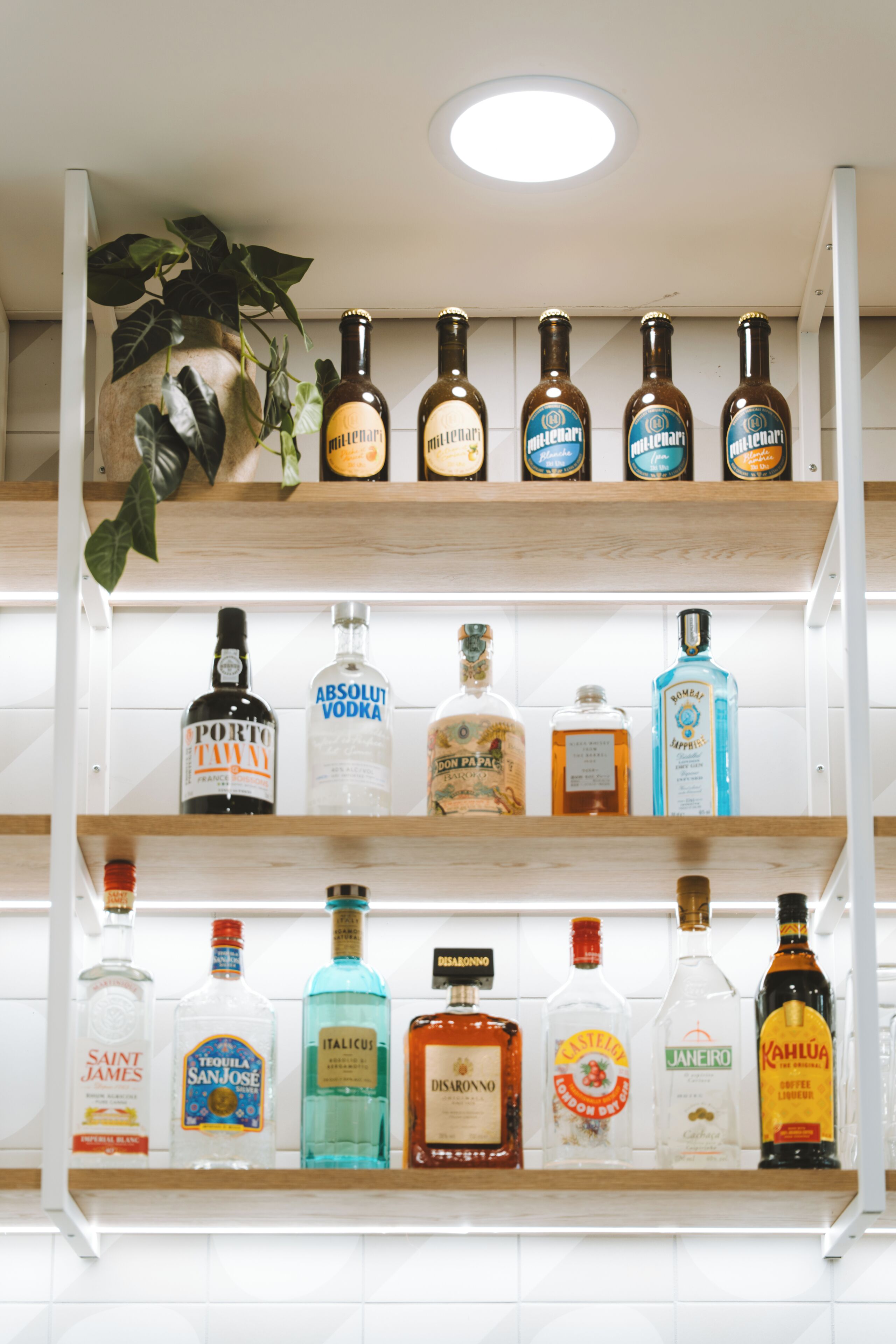 Una estantería con varias botellas de licor, incluyendo vodka Absolut y Kahlúa.