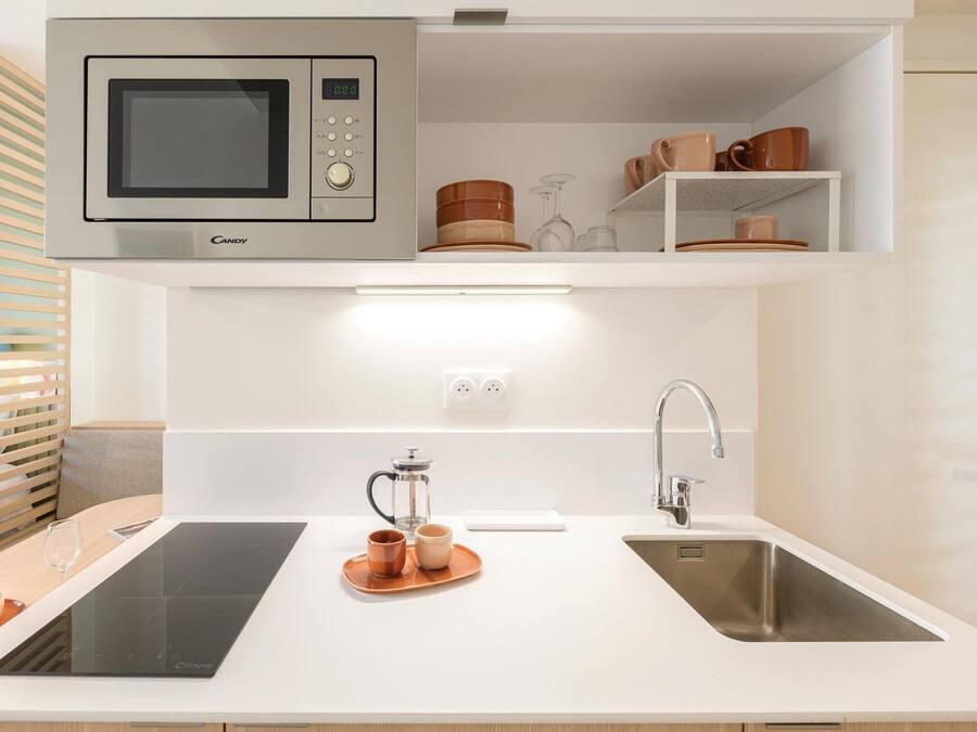 A modern kitchen with a built-in microwave, a sink, and a coffee maker.