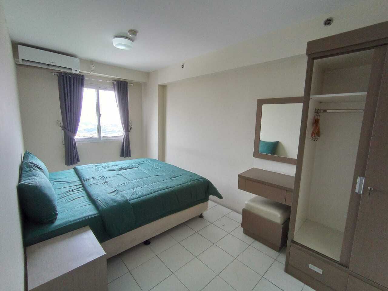A bedroom with a bed, a bedside table, a mirror, a wardrobe, and a window with curtains.