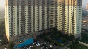 Un edificio de apartamentos alto con varios pisos, un estacionamiento y una piscina.