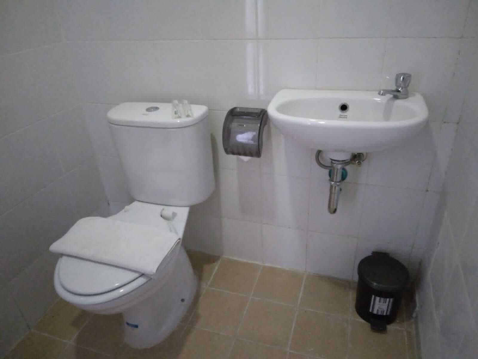Une petite salle de bain avec des toilettes, un lavabo et une poubelle.