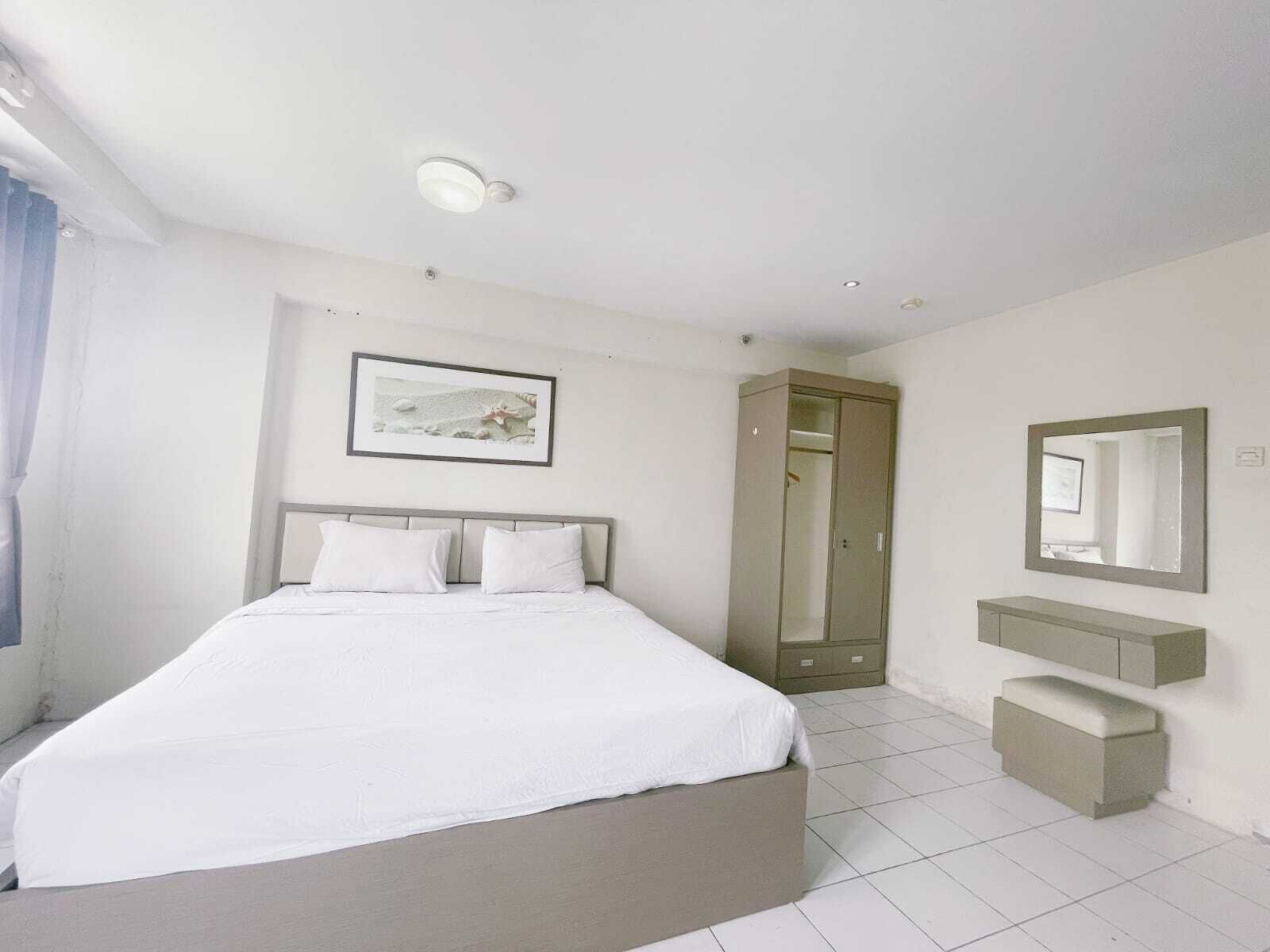 A modern bedroom with a large bed, a walk-in closet, a bedside table, a mirror, and a framed picture on the wall.