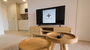Moderni olohuone, jossa on puinen TV-taso, litteänäyttöinen televisio ja kaukosäädin pienellä puupöydällä.