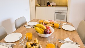 Ruokapöytä on katettu aamiaistarvikkeilla, taustalla näkyy mikroaaltouuni ja pesuallas.