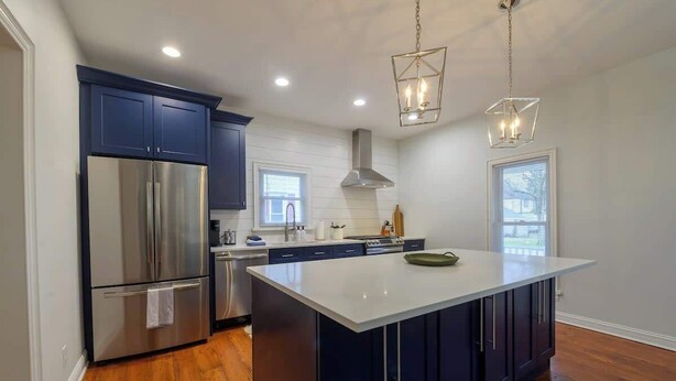 Une cuisine moderne avec des meubles bleu foncé, des appareils en acier inoxydable et un grand îlot central.