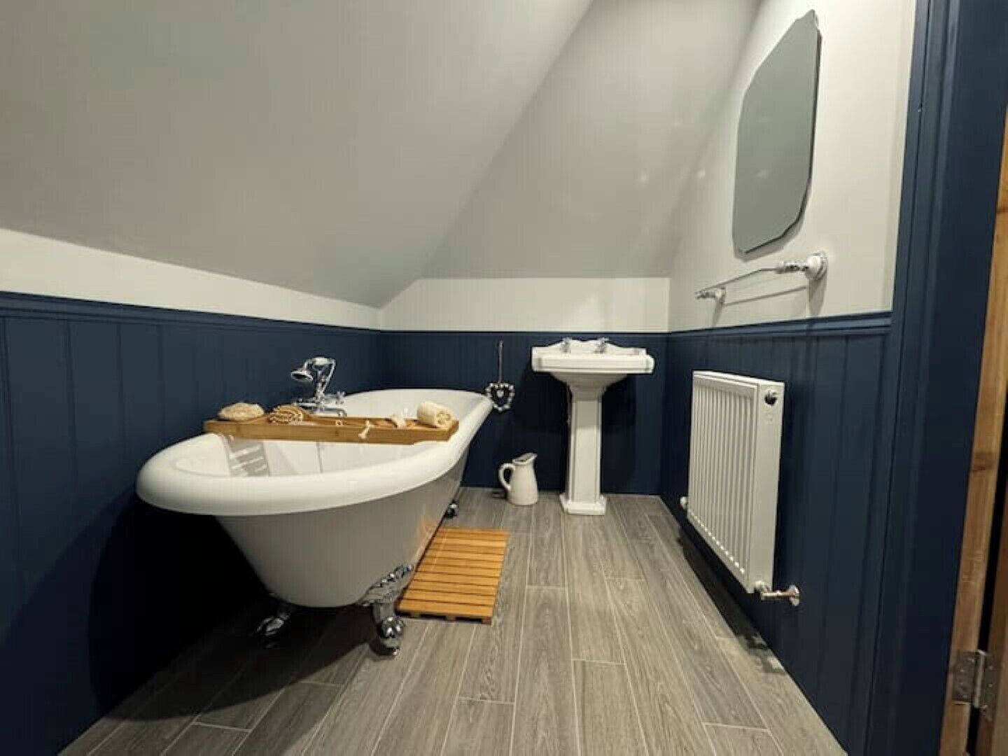 A bathroom with a freestanding bathtub, a pedestal sink, and a radiator.