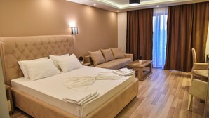 A hotel room with a large bed, a sofa, a small table, and a chair. - Hotel Evropa (Ulcinj)