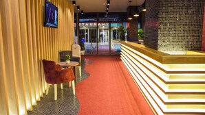 A modern hotel lobby with a reception desk, seating area, and a restaurant entrance. - Hotel Evropa (Ulcinj)
